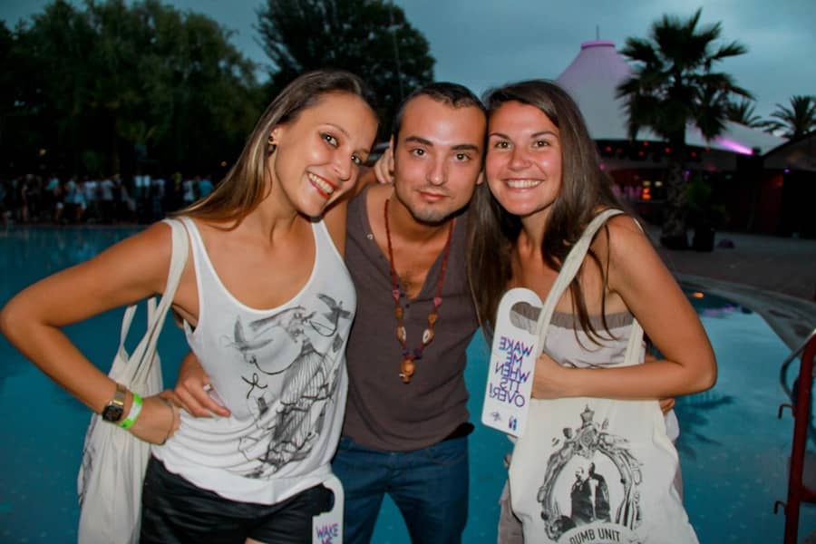 a man with two girl group photo in front of a swimming pool during flyzik music festival in barcelona