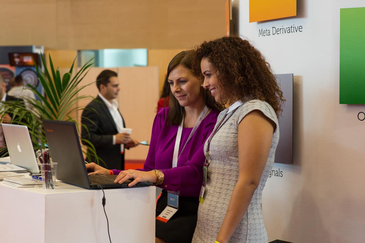 Two women looking at the screen of a laptop during a business event, Audiovisual Production Barcelona