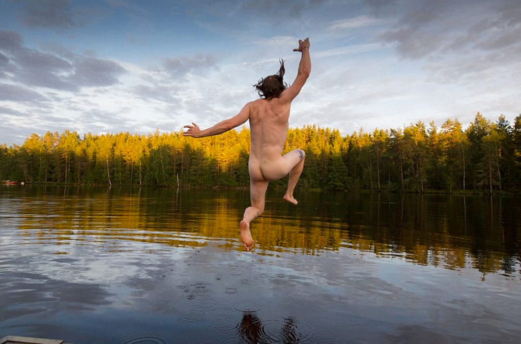 Naked man jumping into lake