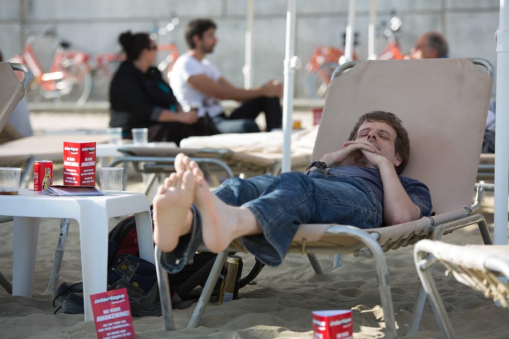 Hombre reposando en una camilla en la playa despues de la fiesta de conferencia iGaming, Productora Audiovisual Barcelona