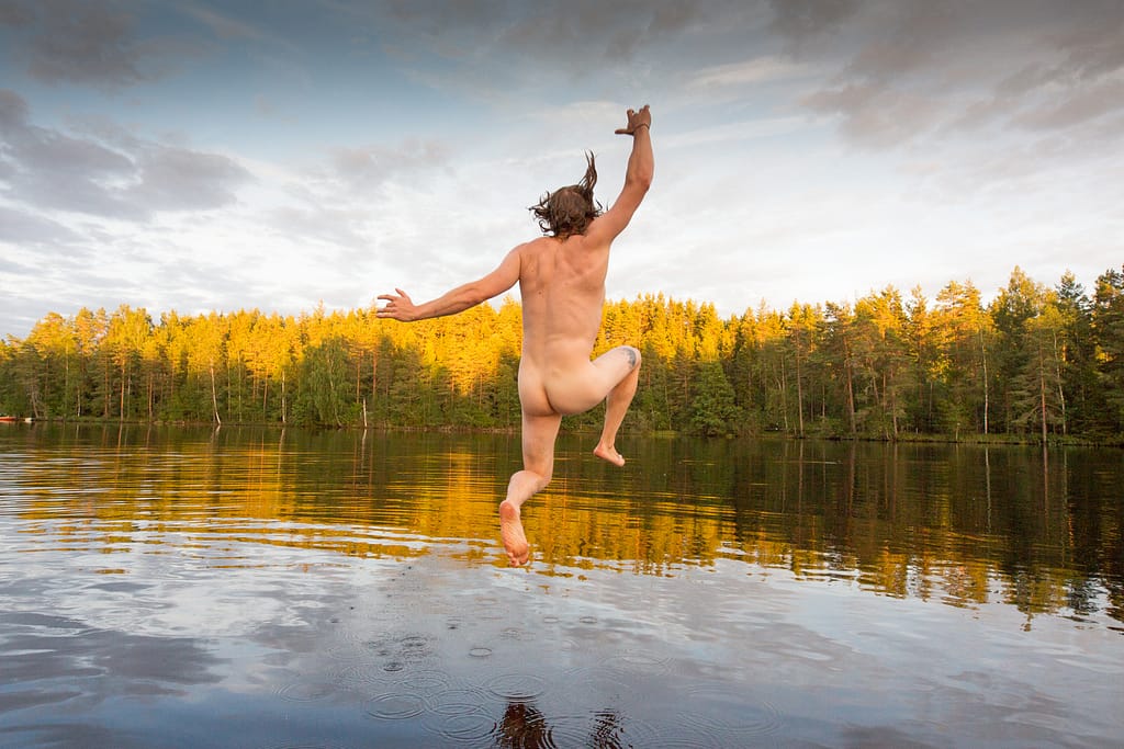 Naked man jumping into a lake