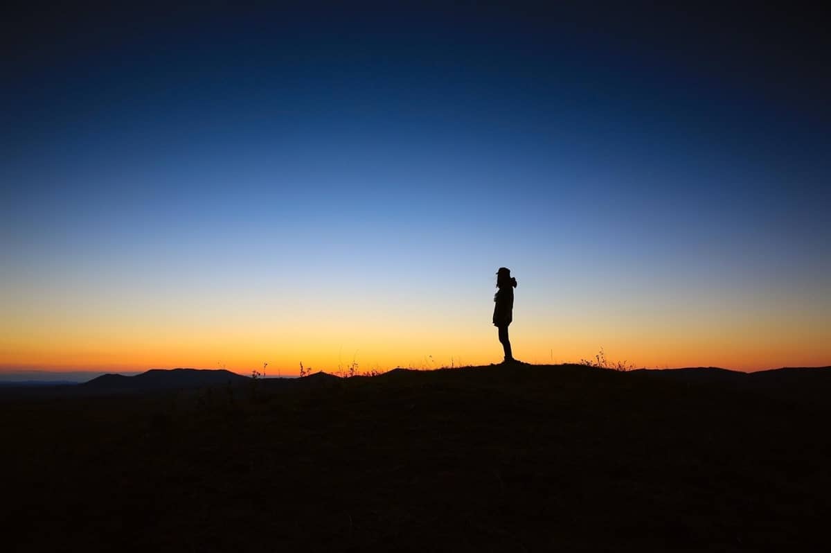 Silhouette image of a person observing the blue and orange sky during a sunset