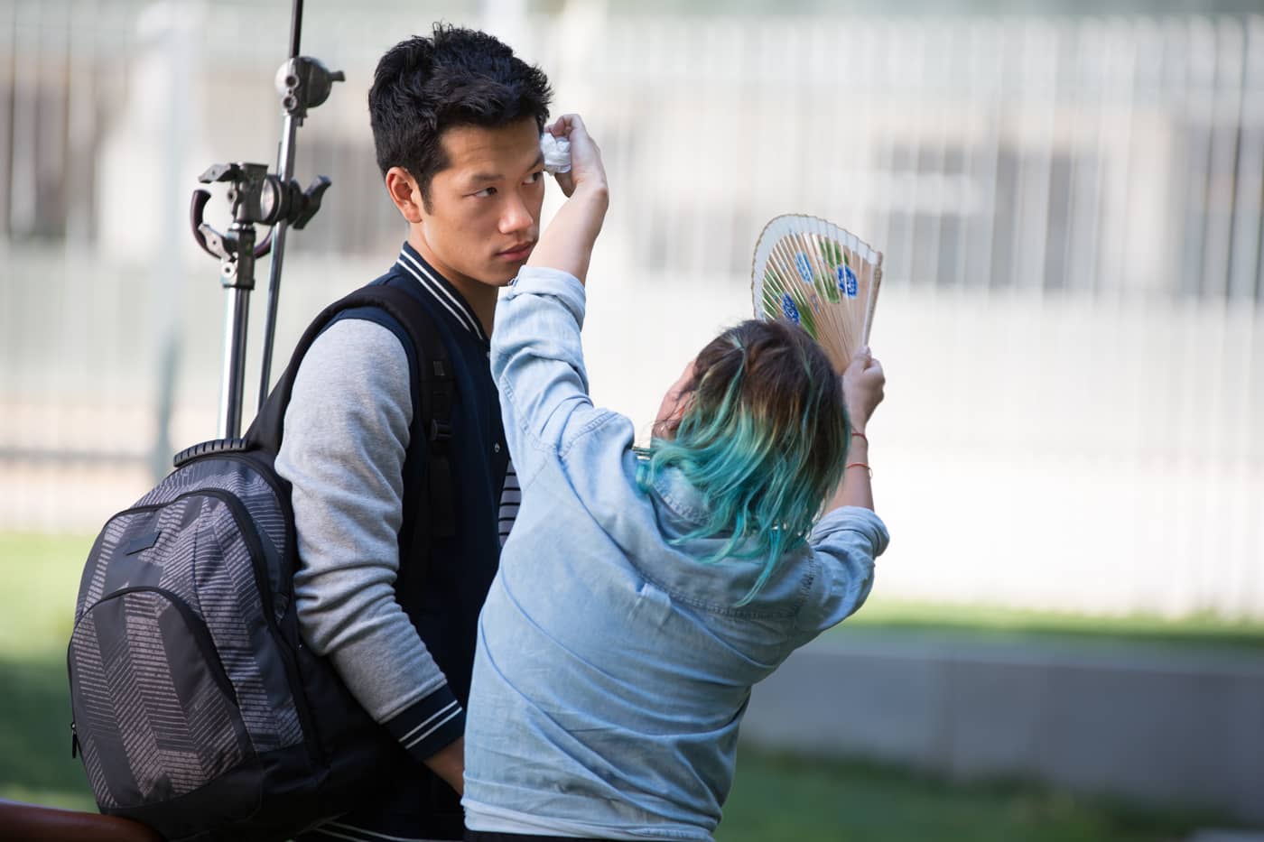 Blue-haired makeup artist applying make-up to young man