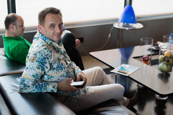 Hombre con camisa colorida sentando en un sofa sosteniendo telefono movil en sus manos, Evento Corporativo Barcelona