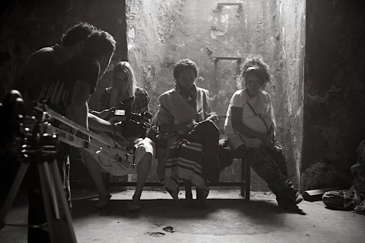 production crew is preparing the camera for work while the accretes are taking a rest on a bench