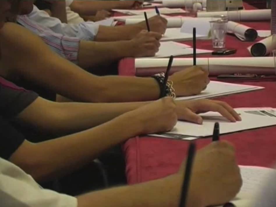 close photograph of writing hands picture taken from a corporate conference video